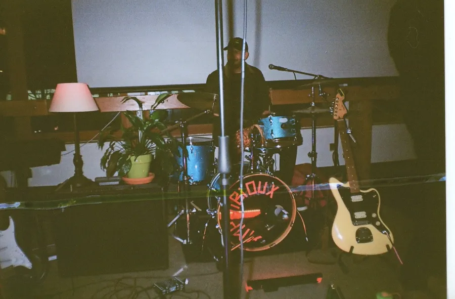 The drum kit between sets, an Amphibioux head on the bass drum and a guitar leaning alongside