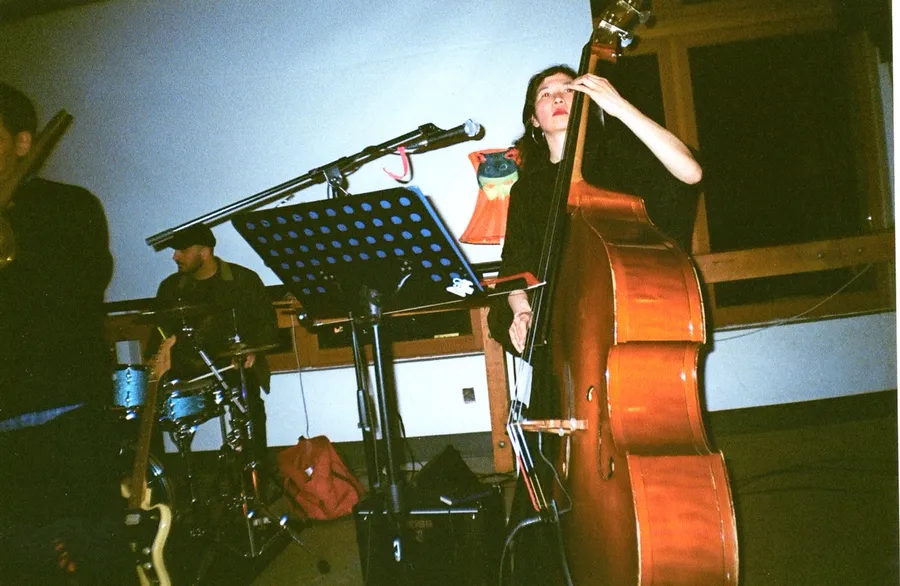 Julia Farry bowing the upright bass, the drummer playing behind her