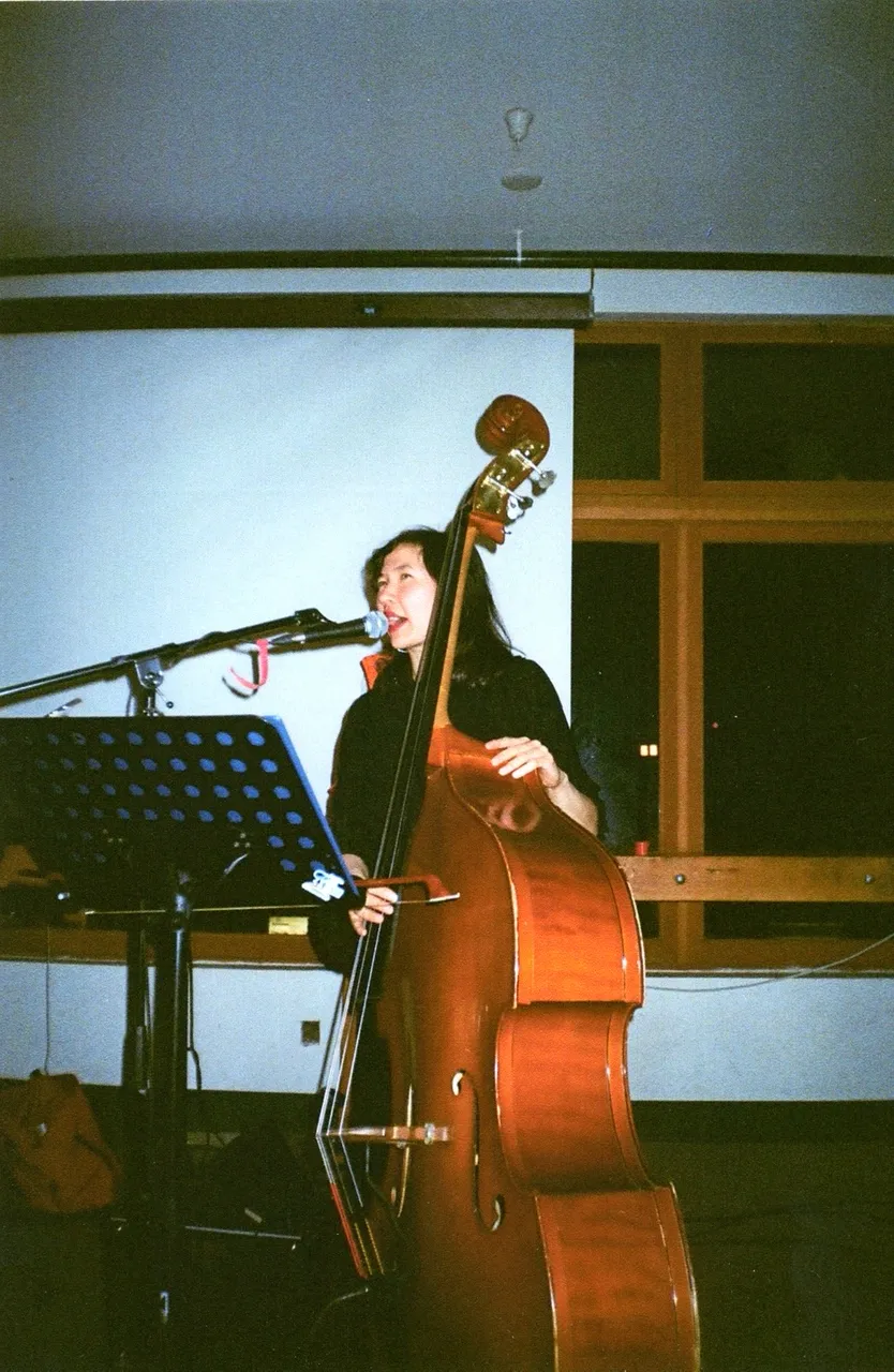 Julia Farry singing at the microphone while playing upright bass