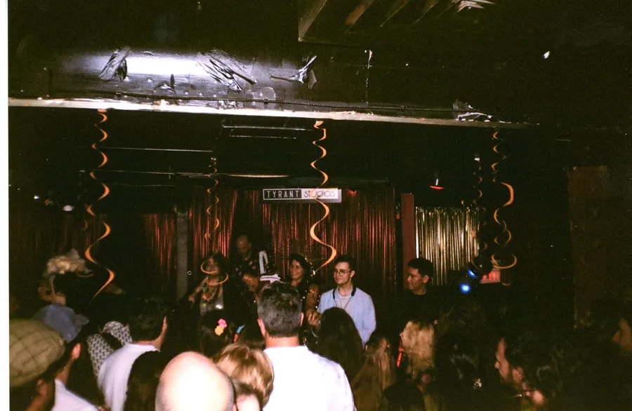 The stage at Tyrant Studios seen over the crowd, orange streamers hanging from the ceiling